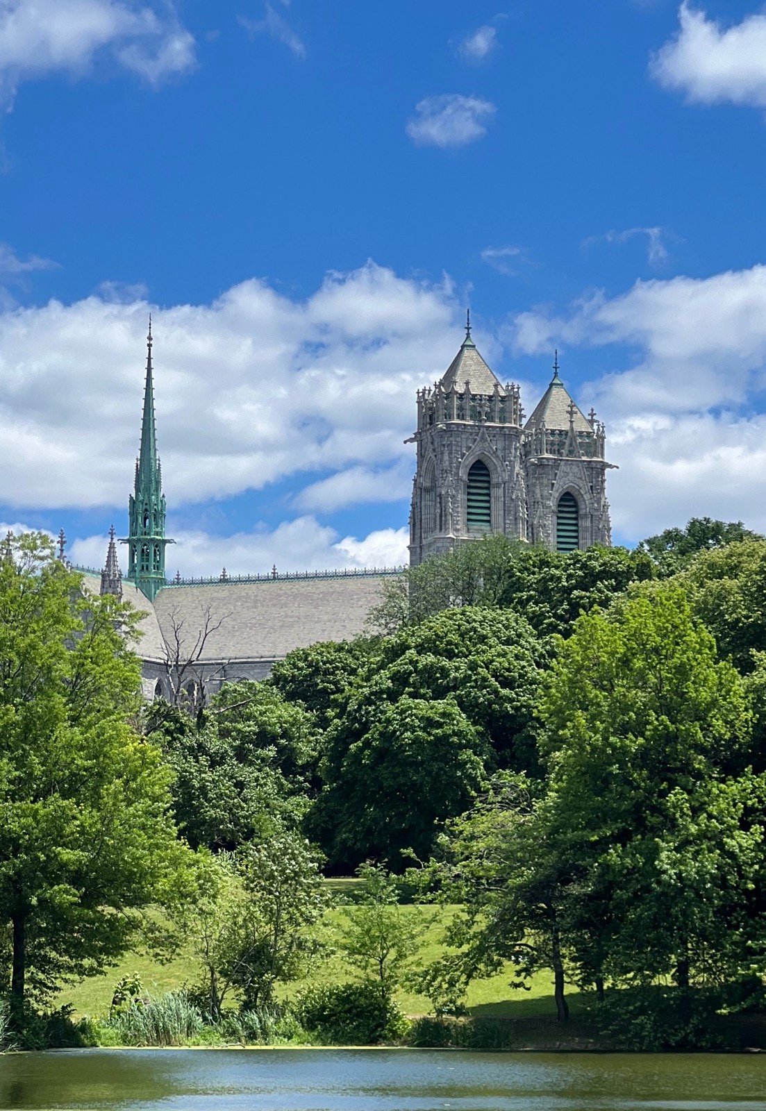 Historic church rising beyond trees beside a lake